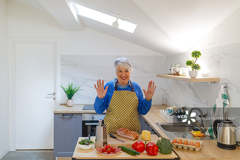 穿着围裙的妇女在家做饭健康晚餐。图片素材