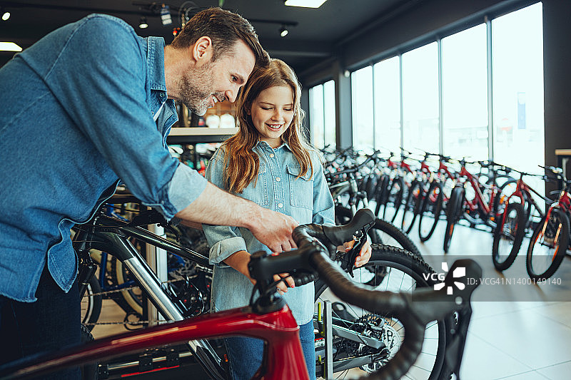 男人和女儿在自行车店测试新的赛车自行车图片素材