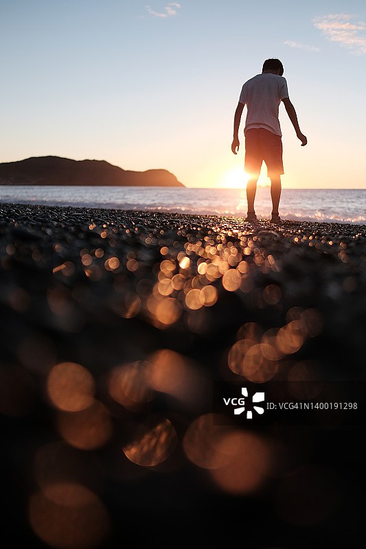 晨曦中，男孩在海边散步图片素材