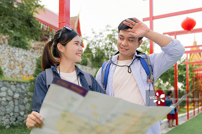 快乐的亚洲情侣在泰国曼谷的寺庙旅行时寻找方向图片素材