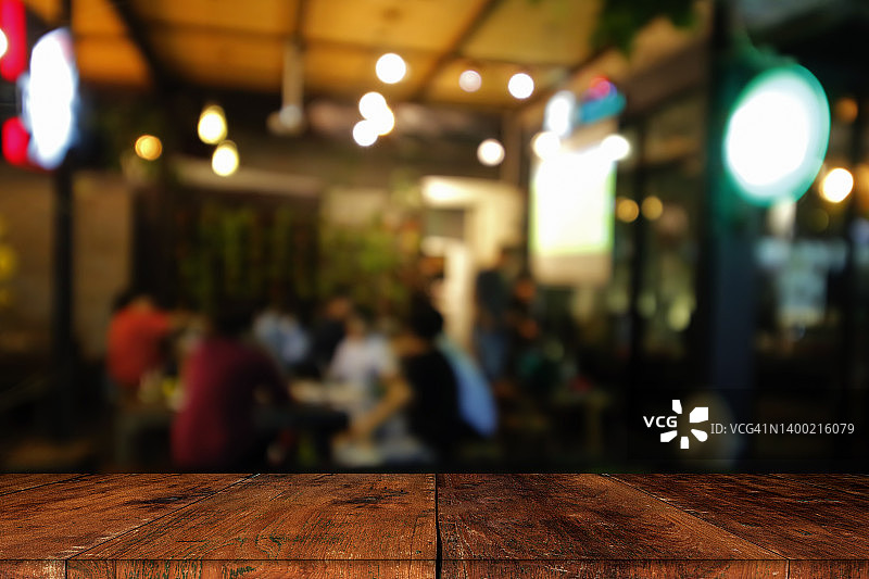夜晚咖啡馆灯光模糊中的木质桌面——庆祝概念图片素材
