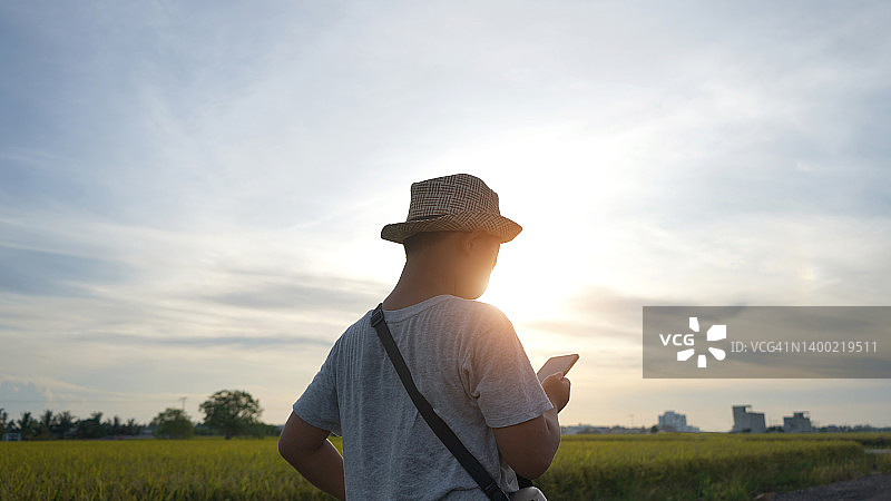 日落时分在户外用手机的男孩图片素材