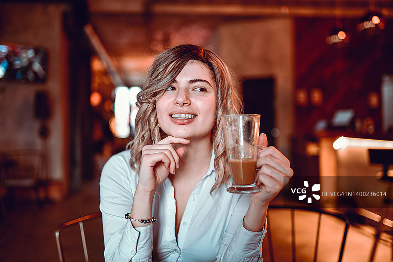 在酒吧等男朋友时喝咖啡的微笑金发女人图片素材