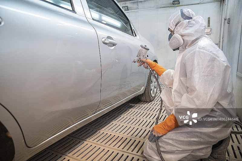 汽车维修店技师用喷枪喷涂汽车零件图片素材