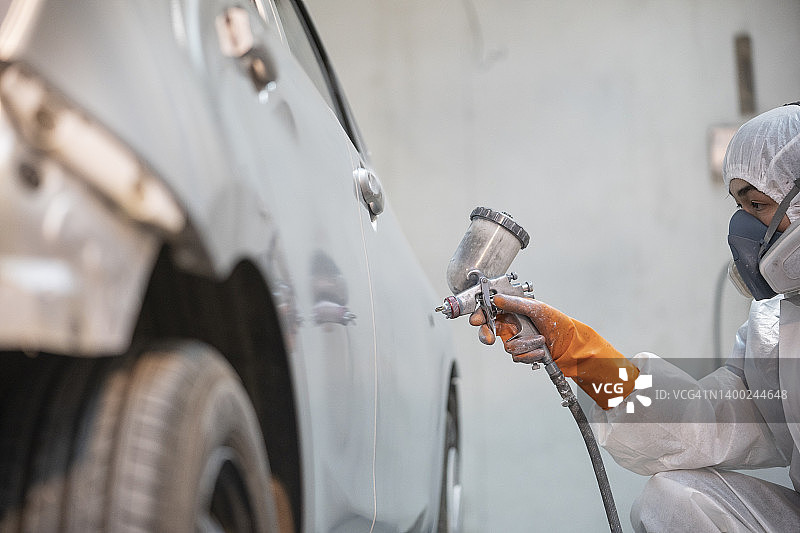 汽车维修店技师用喷枪喷涂汽车零件图片素材