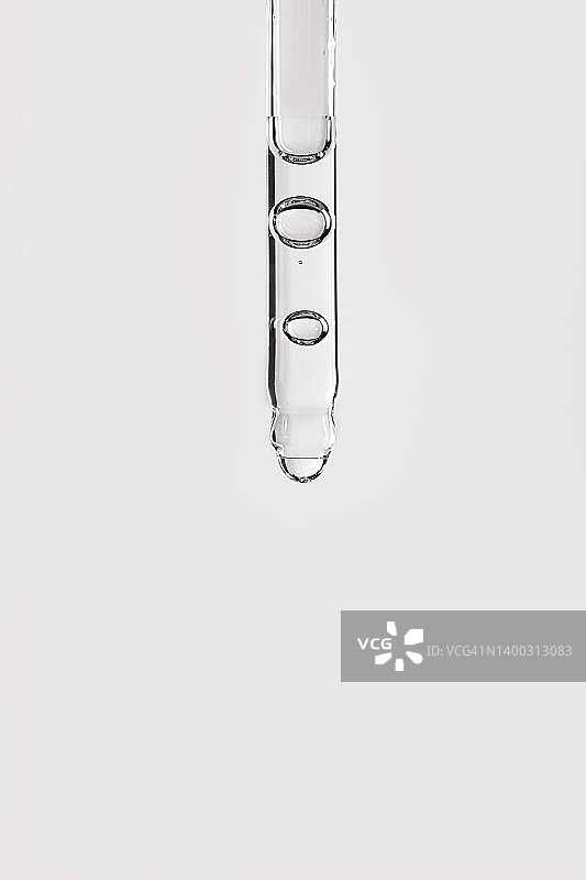 滴管特写：含氧气水泡的面部精华或精油，滴在柔和的灰色背景上图片素材