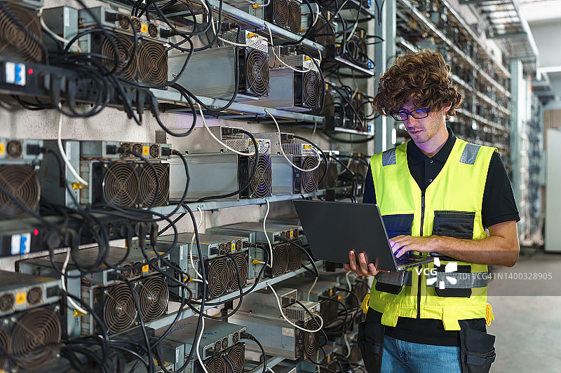 专业工程师携带笔记本电脑在加密货币矿场工作图片素材