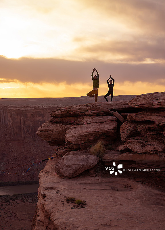 年轻夫妇在犹他州摩押的日落时分练习瑜伽图片素材