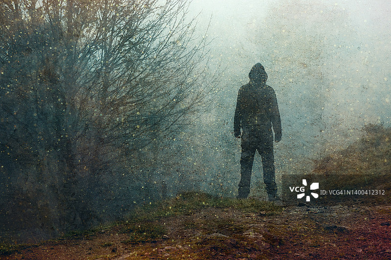 黑暗恐怖概念：乡村阴沉冬日森林中一个幽灵般的身影轮廓，带有粗犷的纹理编辑图片素材