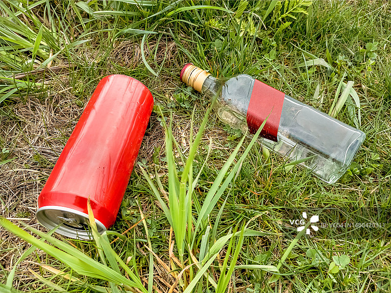 空酒瓶和空苏打罐躺在草地上图片素材