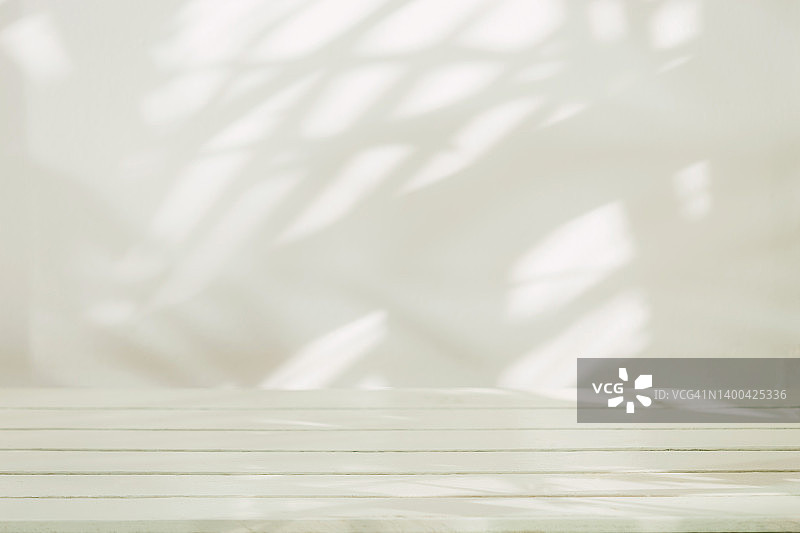 混凝土墙上带有阴影叶子的空木桌，用于背景和产品展示图片素材