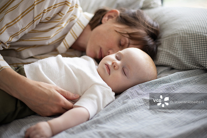 6个月大的婴儿和妈妈在家里的床上睡觉图片素材