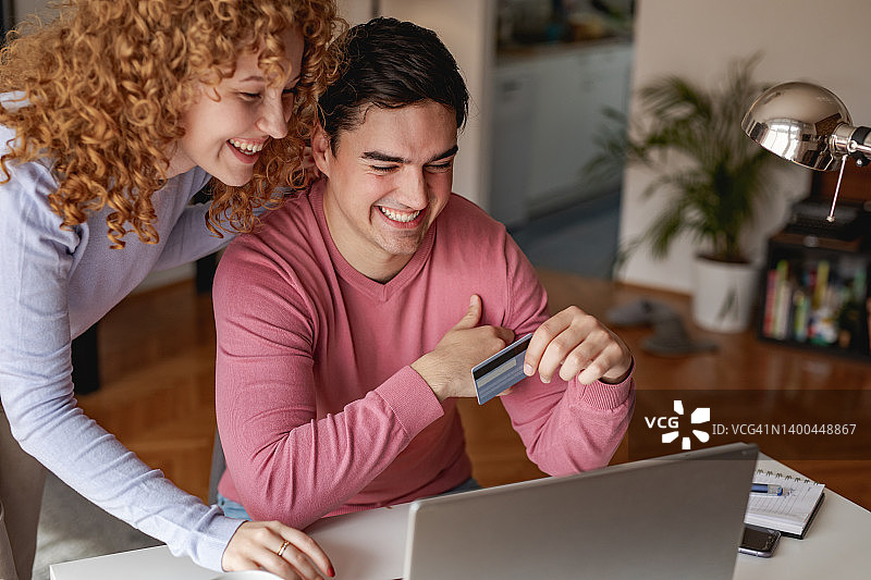 使用笔记本电脑的快乐年轻夫妇的肖像图片素材