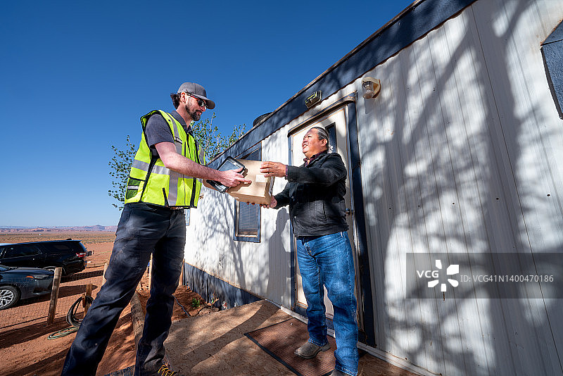 男子在小镇的组合房屋里给老年男子送包裹图片素材