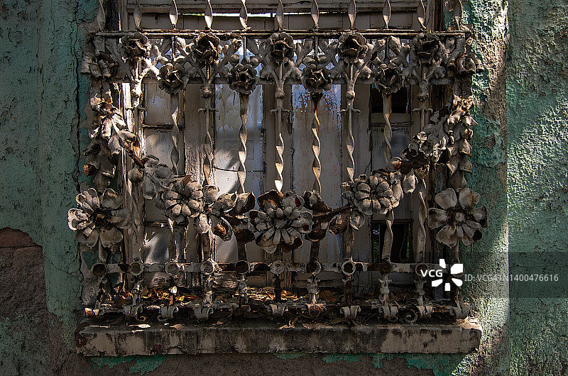废弃房屋窗户上生锈的装饰性花卉安全格栅图片素材