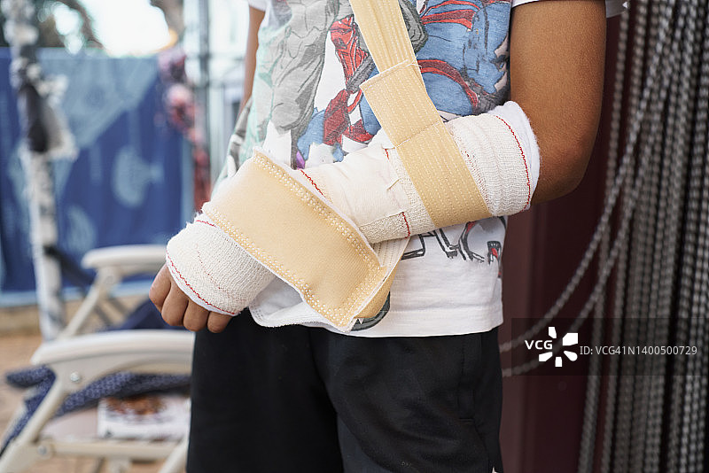 男孩手臂的细节正面图，有绷带和保护胶带图片素材