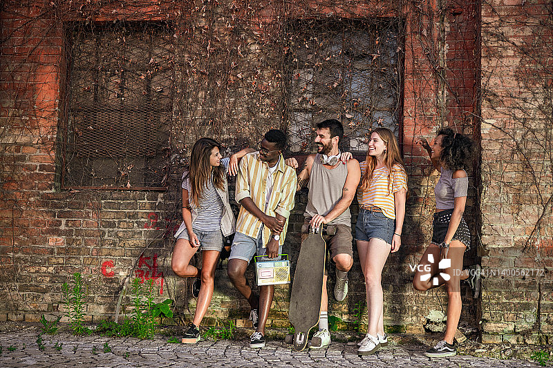 在街头墙边交谈的快乐朋友们图片素材
