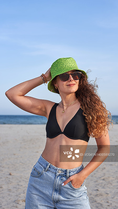 戴着遮阳帽和太阳镜在海滩上享受暑假的女人图片素材