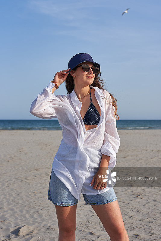 戴着遮阳帽和太阳镜在海滩上享受暑假的女人图片素材