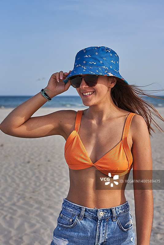 海边女孩戴渔夫帽墨镜，享受夏日假期图片素材