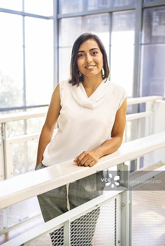 在办公室里靠着栏杆的年轻女商人图片素材