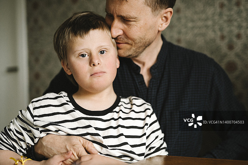 患有唐氏综合征的男孩与父亲在家中的肖像图片素材