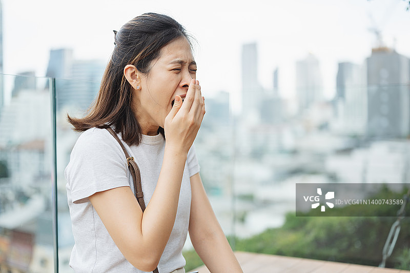在办公室工作一天的年轻亚洲女性打哈欠图片素材