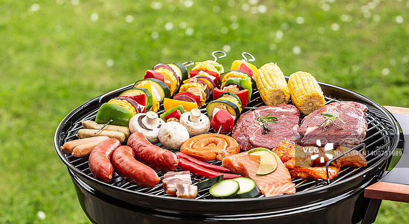 烤架上的香肠、红肉、三文鱼、蘑菇、肉串、鸡翅、培根和玉米图片素材