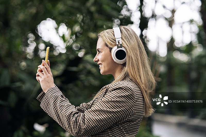 在城市里戴着耳机和手机的金发女人图片素材