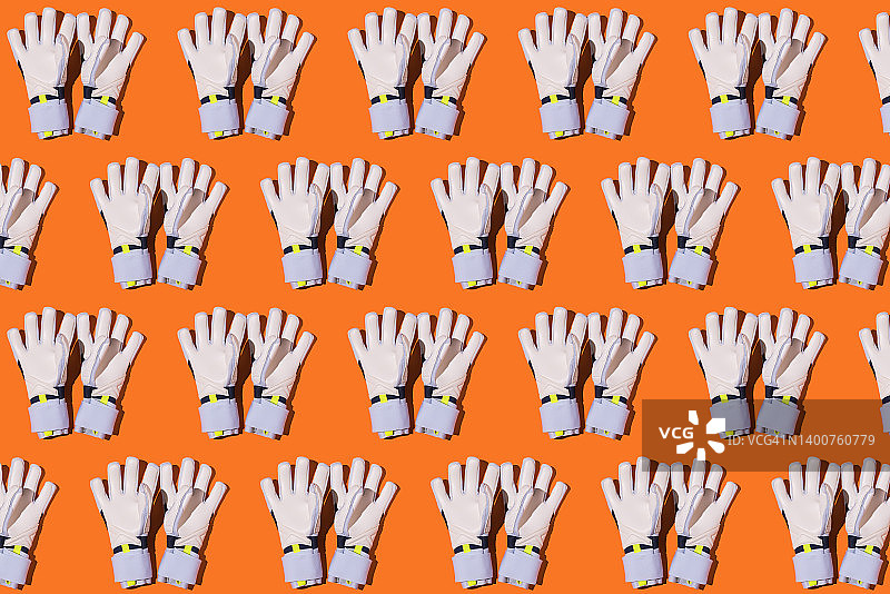 橙色背景上的白色守门员手套，足球、运动、比赛和世界冠军概念图片素材