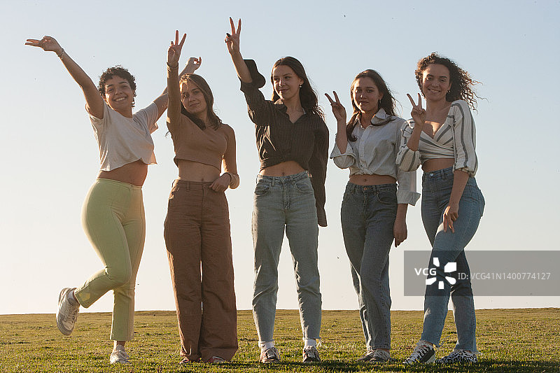 五位年轻女子在公园或海边一起摆V字造型图片素材