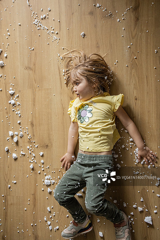 玩耍时完全被泡沫塑料球覆盖，在地上旋转的可爱小女孩图片素材