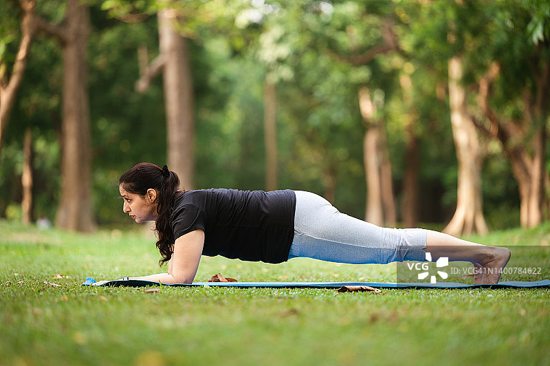 年轻女子在公园的地面上做平板支撑图片素材