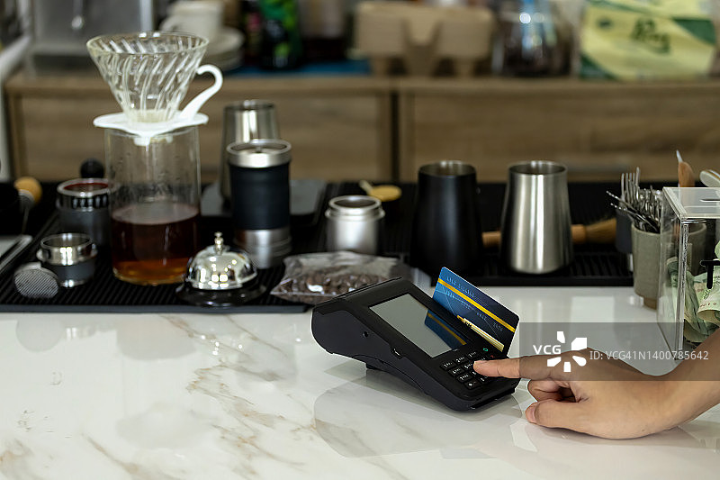 女人在咖啡馆的信用卡读卡机上刷卡支付图片素材