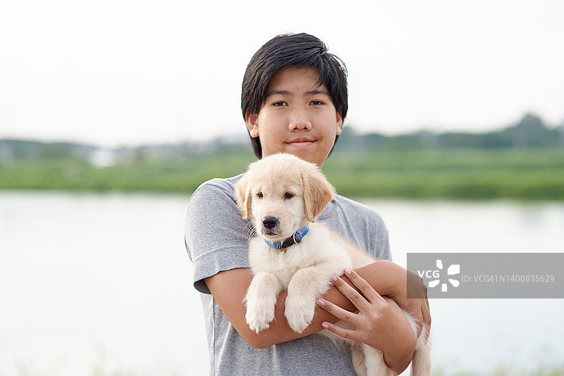 抱着小狗，笑容灿烂的男孩图片素材