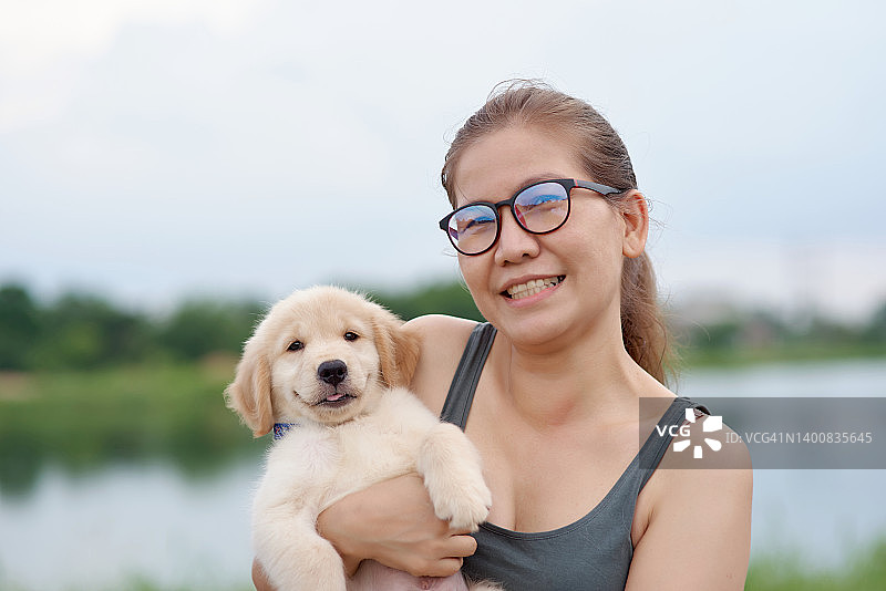 一位抱着小狗，笑容灿烂的女人图片素材