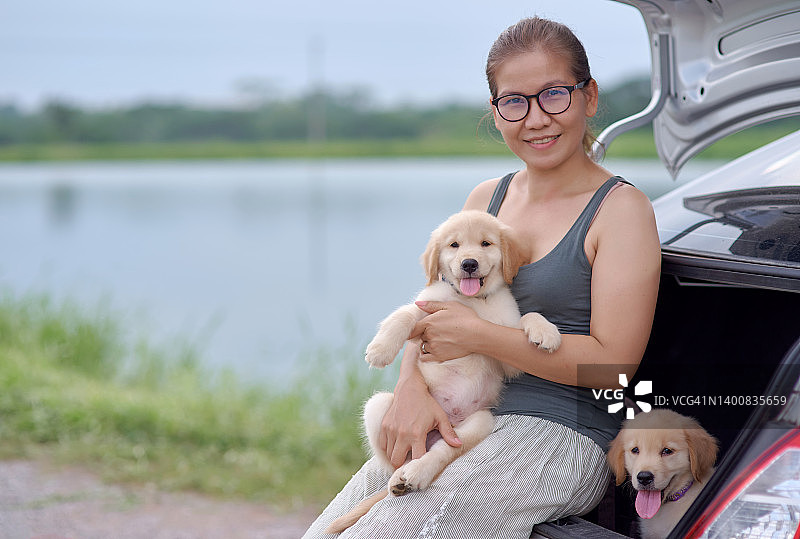 坐在汽车后座、抱着小狗的亚洲女人图片素材