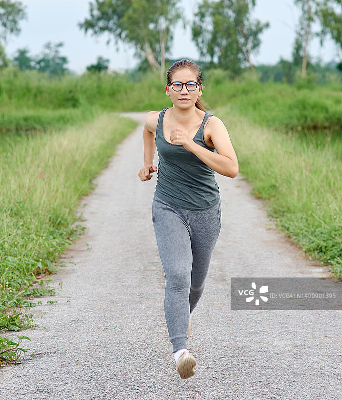 在乡村沥青路上跑步的女人正面图图片素材