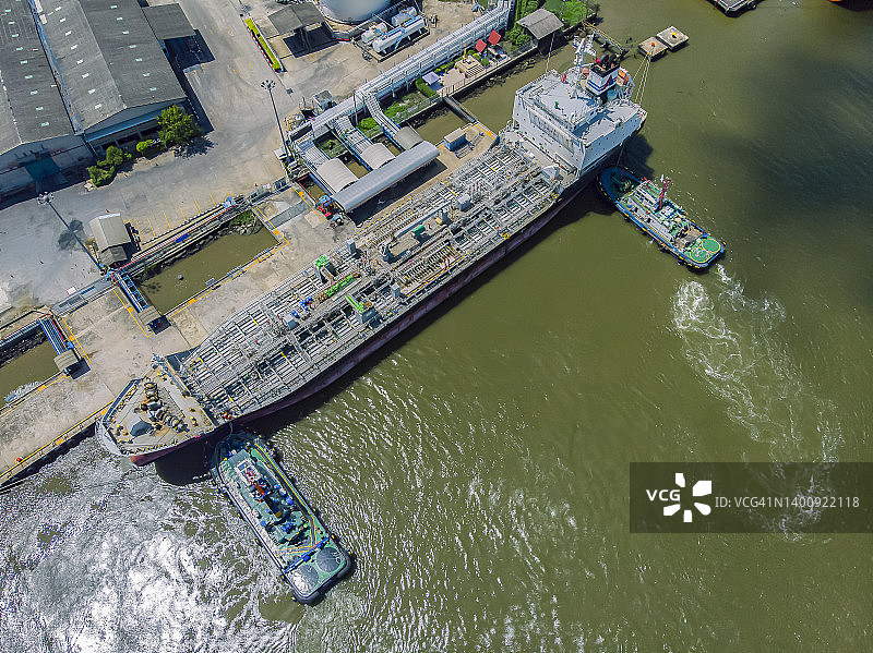 航拍：拖船拖运油轮驶离河边石油港口图片素材