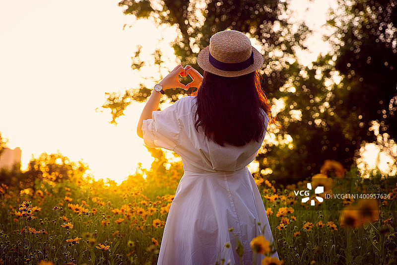 女人们在日落时用手比心图片素材