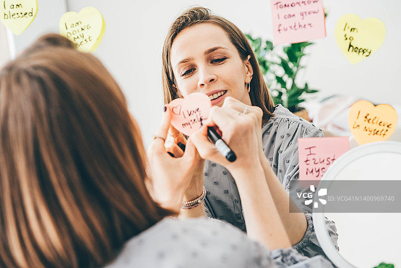 在镜子附近的贴纸上写肯定的女人图片素材