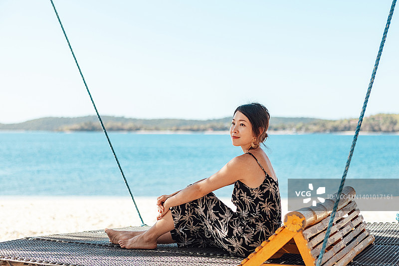 年轻亚洲女人在海滩的秋千椅上放松图片素材