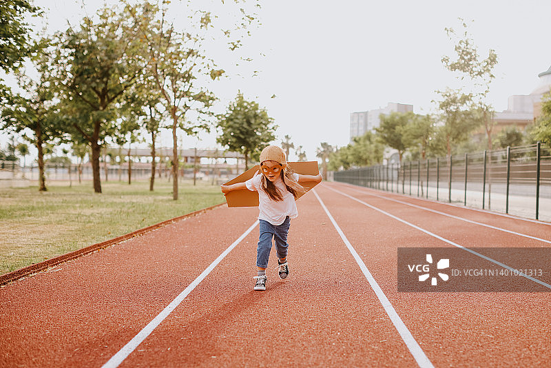 快乐的幼儿女孩在跑道上玩耍图片素材