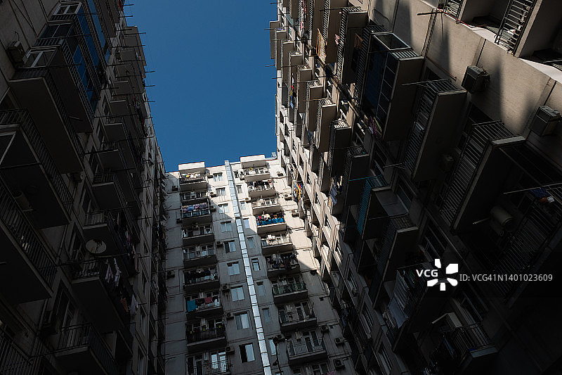 干净的毛衣和裤子在夏日阳光下晾干，洗过的男女儿童衣服、床上用品挂在住宅多层建筑阳台的晾衣绳上，家庭作业、家务的概念图片素材