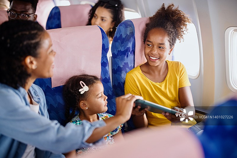 母亲在飞机上给孩子们着色本和平板电脑解闷图片素材