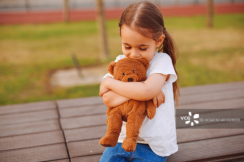 户外抱着玩具小狗的忧伤白人小女孩图片素材