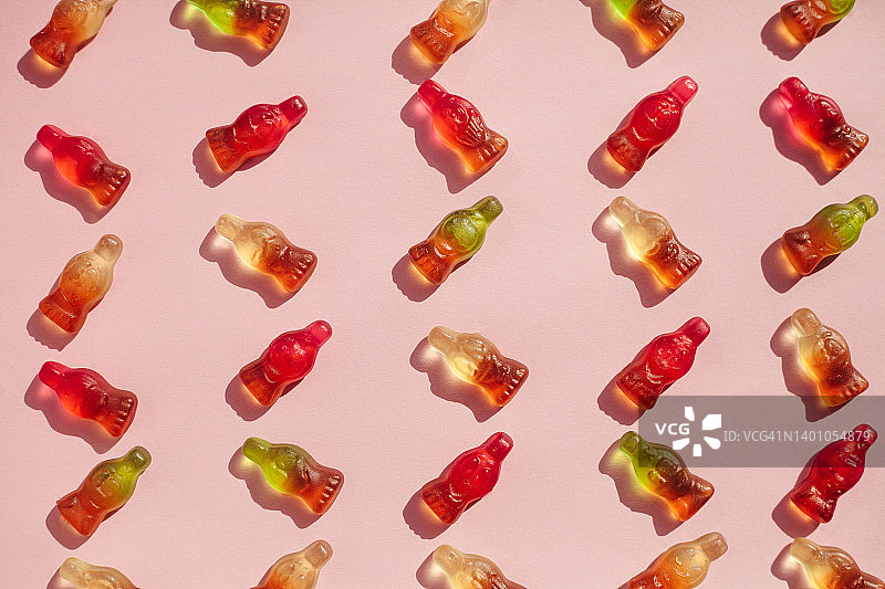 粉色背景上的软糖苏打瓶夏季图案，硬光带阴影图片素材