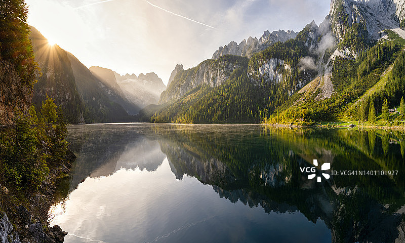 奥地利日出景观：森林、薄雾、草地和环绕湖泊的阿尔卑斯山图片素材