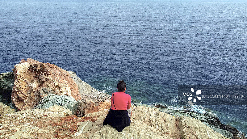 日出时分，女徒步者在海岸悬崖上放松图片素材