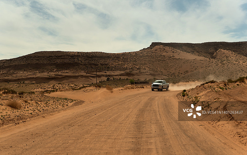 纪念碑谷日落时分在土路上飞驰的皮卡车图片素材